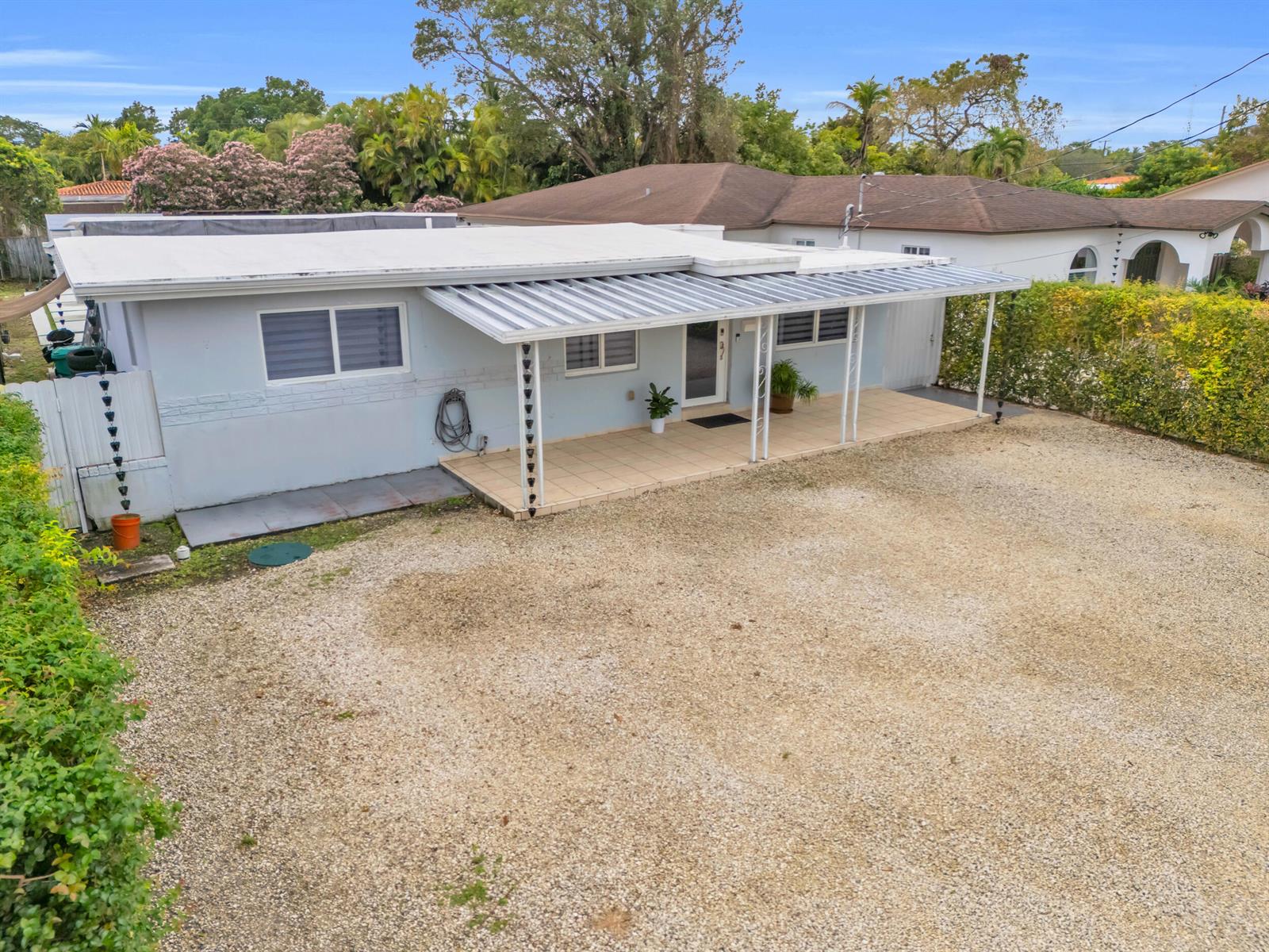 A light blue single-story house features a gravel driveway and a covered front porch — 6350 SW 32 Street, Miami FL 33155, MIAMI, FL