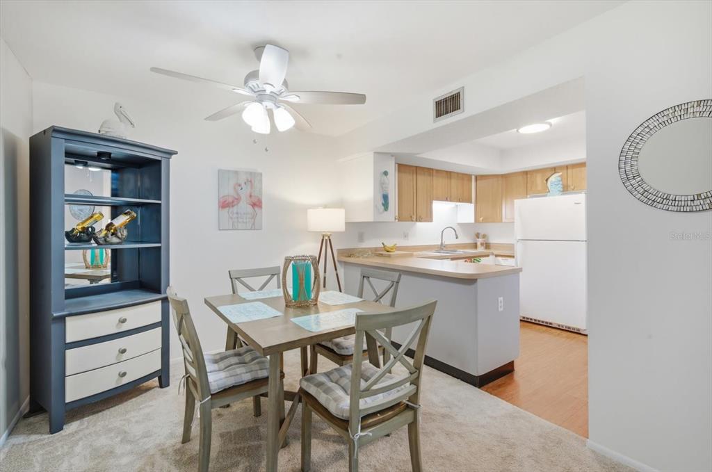 A living room with beige carpet, a large television, an armchair, and an adjacent sunroom — 6108 PENNY LANE, BRADENTON, FL