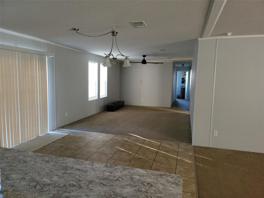 An open-concept living area features a tiled kitchen foreground, carpeted floor, and a chandelier — 8915 HAMMOCK LOOP, POLK CITY, FL 33868, POLK CITY, FL