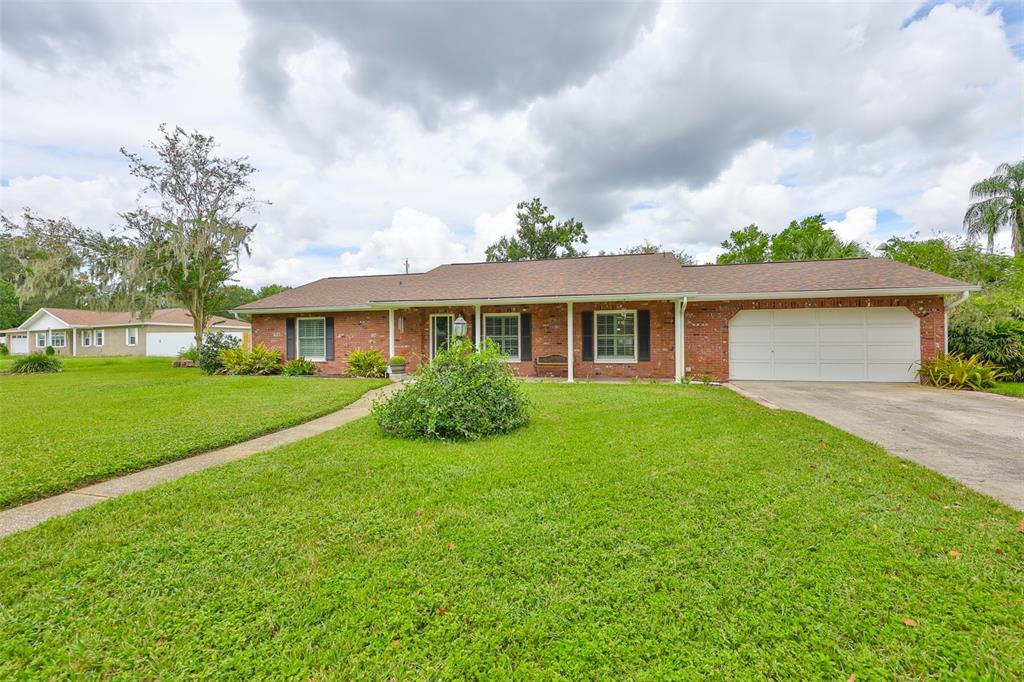 A single-story brick house with a white garage door and a large front lawn — 1408 MOSS LADEN COURT, BRANDON, FL