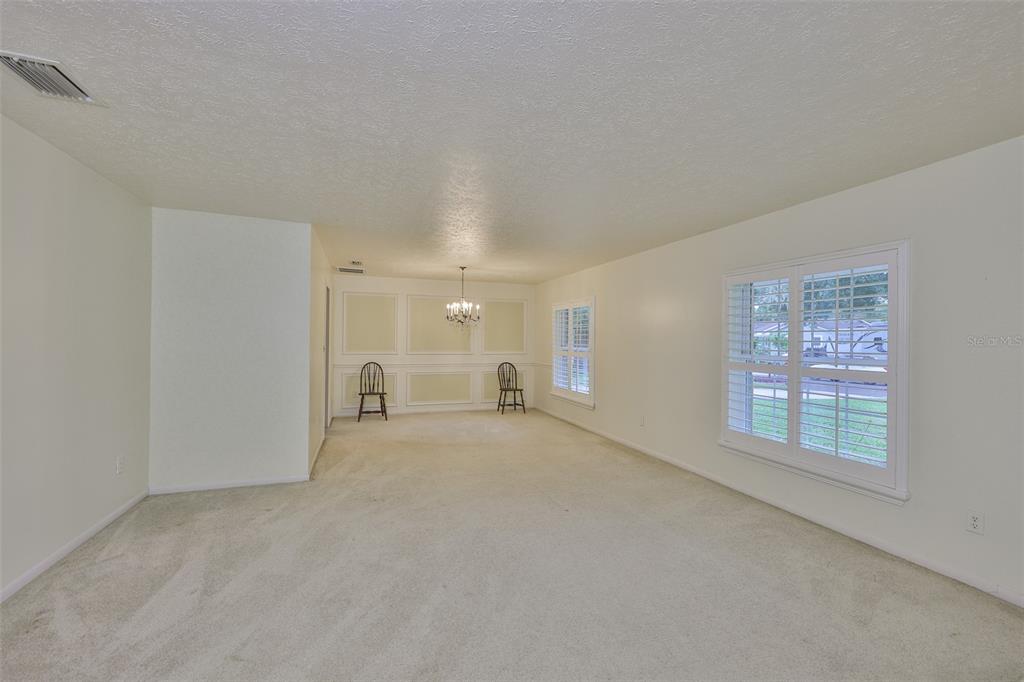 A dining room with beige carpet, white walls, wainscoting, and plantation shutters on the windows — 1408 MOSS LADEN COURT, BRANDON, FL