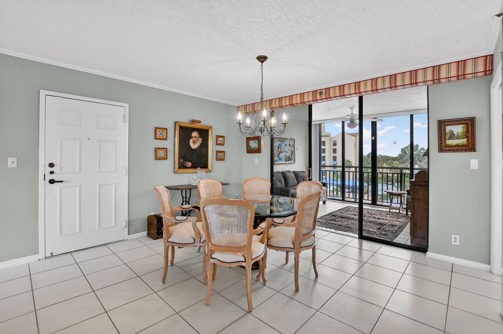 A dining room with a glass table, cane-back chairs, tiled floors, and a balcony view — 7170 Promenade Drive # 401, Boca Raton FL 33433, BOCA RATON, FL