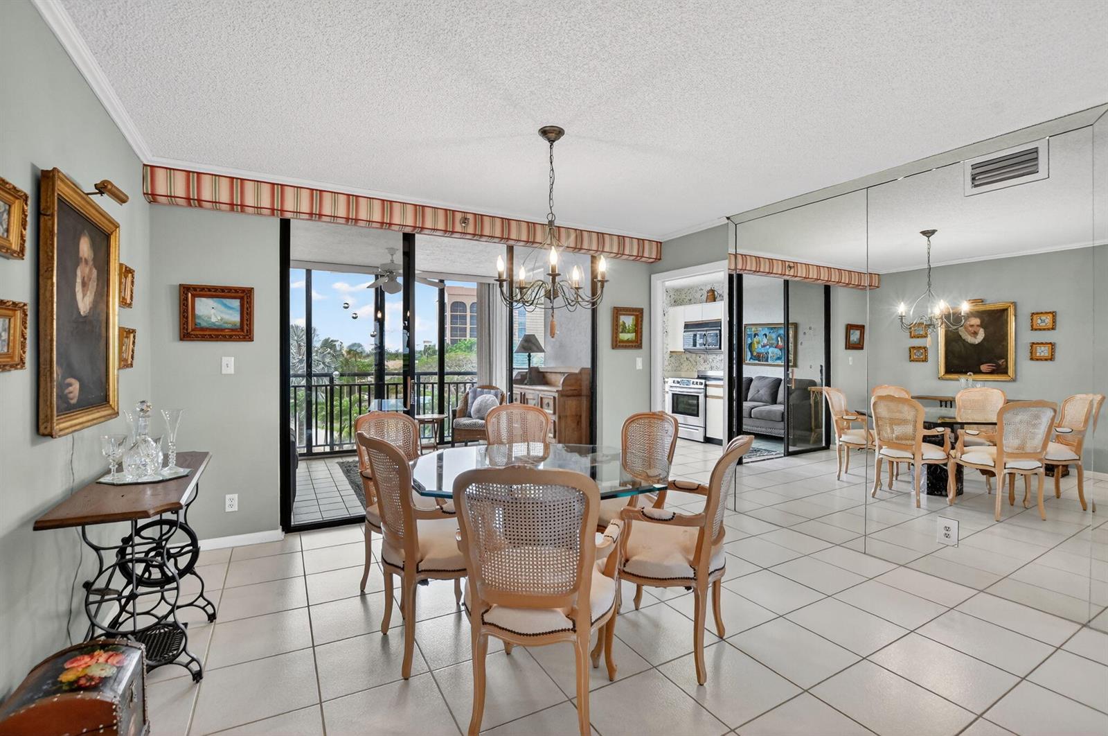 A dining room with a glass table, cane-back chairs, tiled floors, and a mirrored wall — 7170 Promenade Drive # 401, Boca Raton FL 33433, BOCA RATON, FL