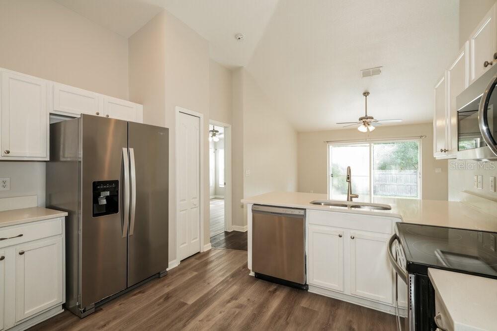 A kitchen with white cabinets, stainless steel appliances, and wood-look flooring — 6410 BUCKHEAD COURT, WESLEY CHAPEL, FL