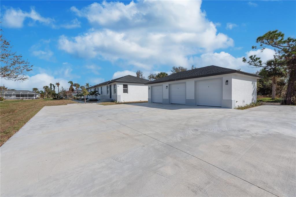 A white house with a three-car garage and a large concrete driveway under a blue sky — 260 ROTONDA BOULEVARD, ROTONDA WEST, FL