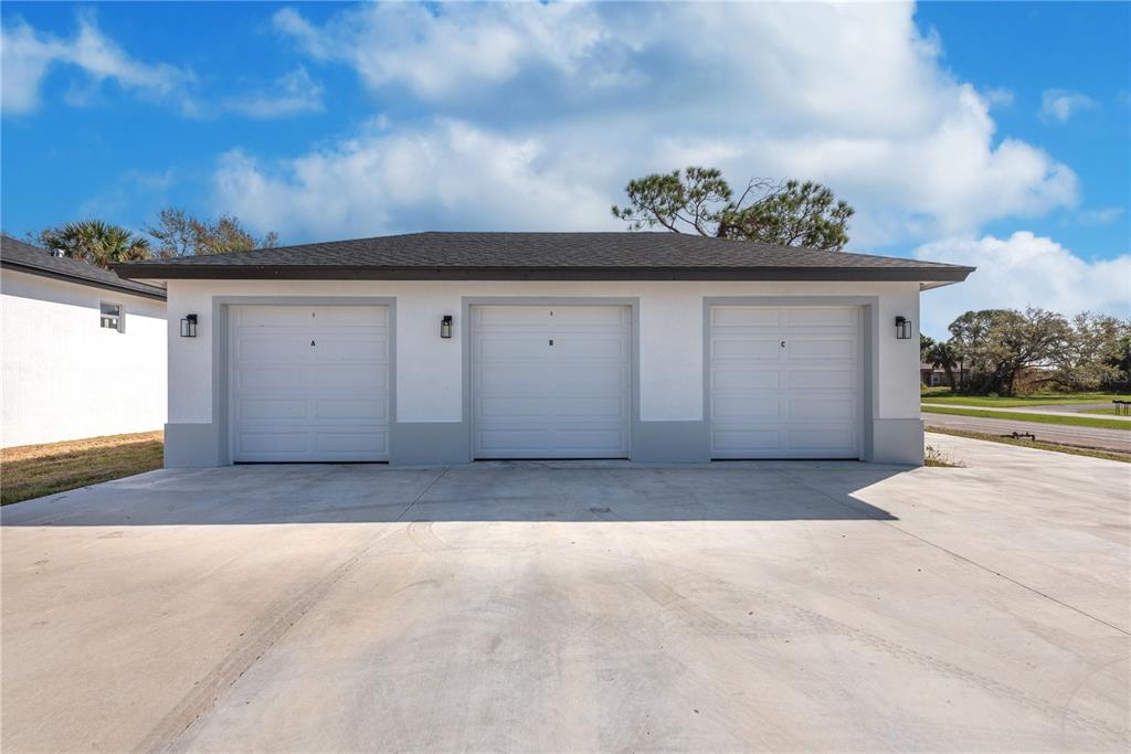 A detached three-car garage with white stucco walls and a gray shingled roof — 260 ROTONDA BOULEVARD, ROTONDA WEST, FL