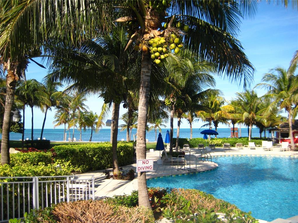 A swimming pool sits near palm trees and a beach under a clear blue sky — 802 GRAN BAHAMA BOULEVARD UNIT 802, DAVENPORT, FL