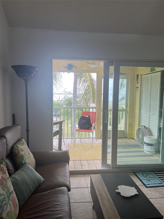 A living room with a brown sofa and sliding glass doors opening to a screened porch — 9400 LITTLE GASPARILLA ISLAND UNIT A7, PLACIDA, FL