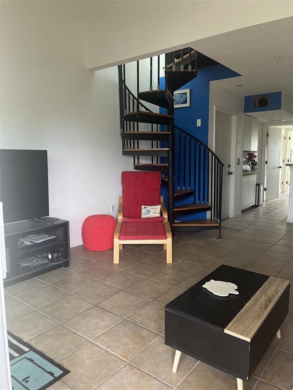 A living room features a spiral staircase, tile flooring, a red chair, and a coffee table — 9400 LITTLE GASPARILLA ISLAND UNIT A7, PLACIDA, FL