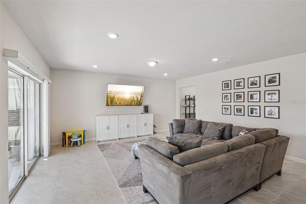 A living room features a gray sectional sofa, a wall-mounted television, and a white console — 2210 LOVELY LANE, DAVENPORT, FL