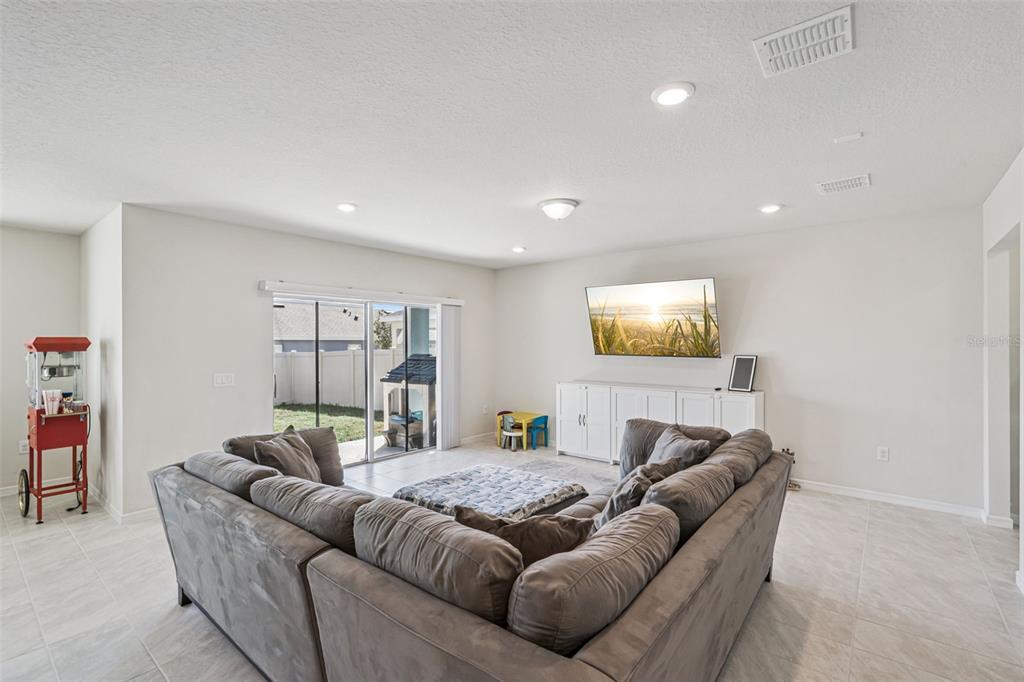 A living room features a large gray sectional sofa, a wall-mounted television, and tile flooring — 2210 LOVELY LANE, DAVENPORT, FL