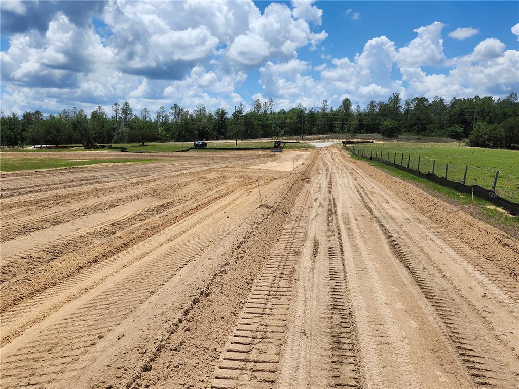 A dirt construction site features tire tracks leading toward a treeline under a cloudy sky — 0 CHRISTIAN ROAD Lot 1, DADE CITY, FL
