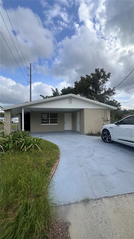 A single-story house with a covered carport and a light blue painted driveway — 3311 E CHELSEA STREET, TAMPA, FL