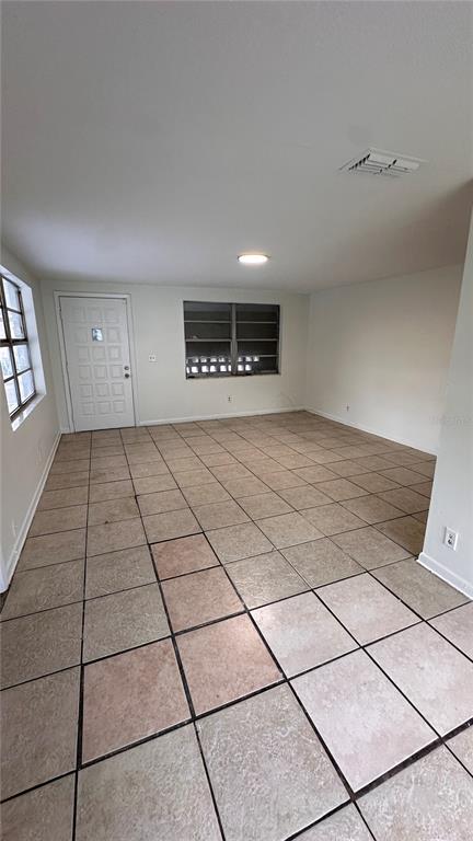 An empty room with light-colored tile flooring, white walls, a window, and a white door — 3311 E CHELSEA STREET, TAMPA, FL