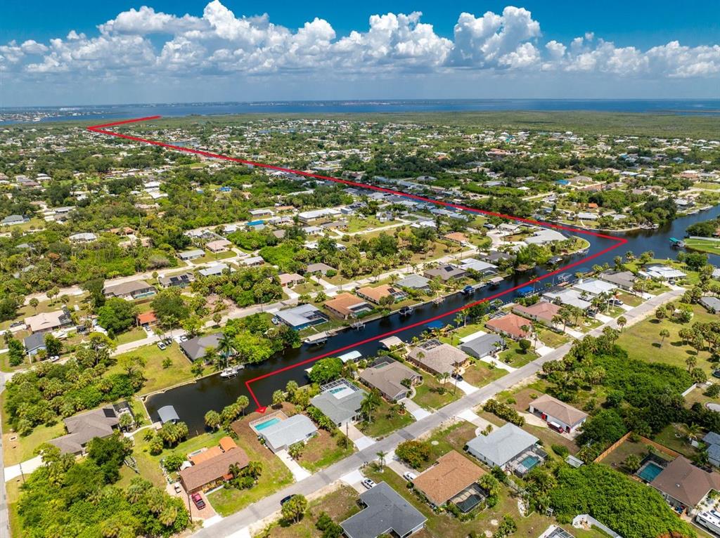 An aerial view shows a residential neighborhood with a canal and a red property boundary line — 18321 WOLBRETTE CIRCLE, PORT CHARLOTTE, FL