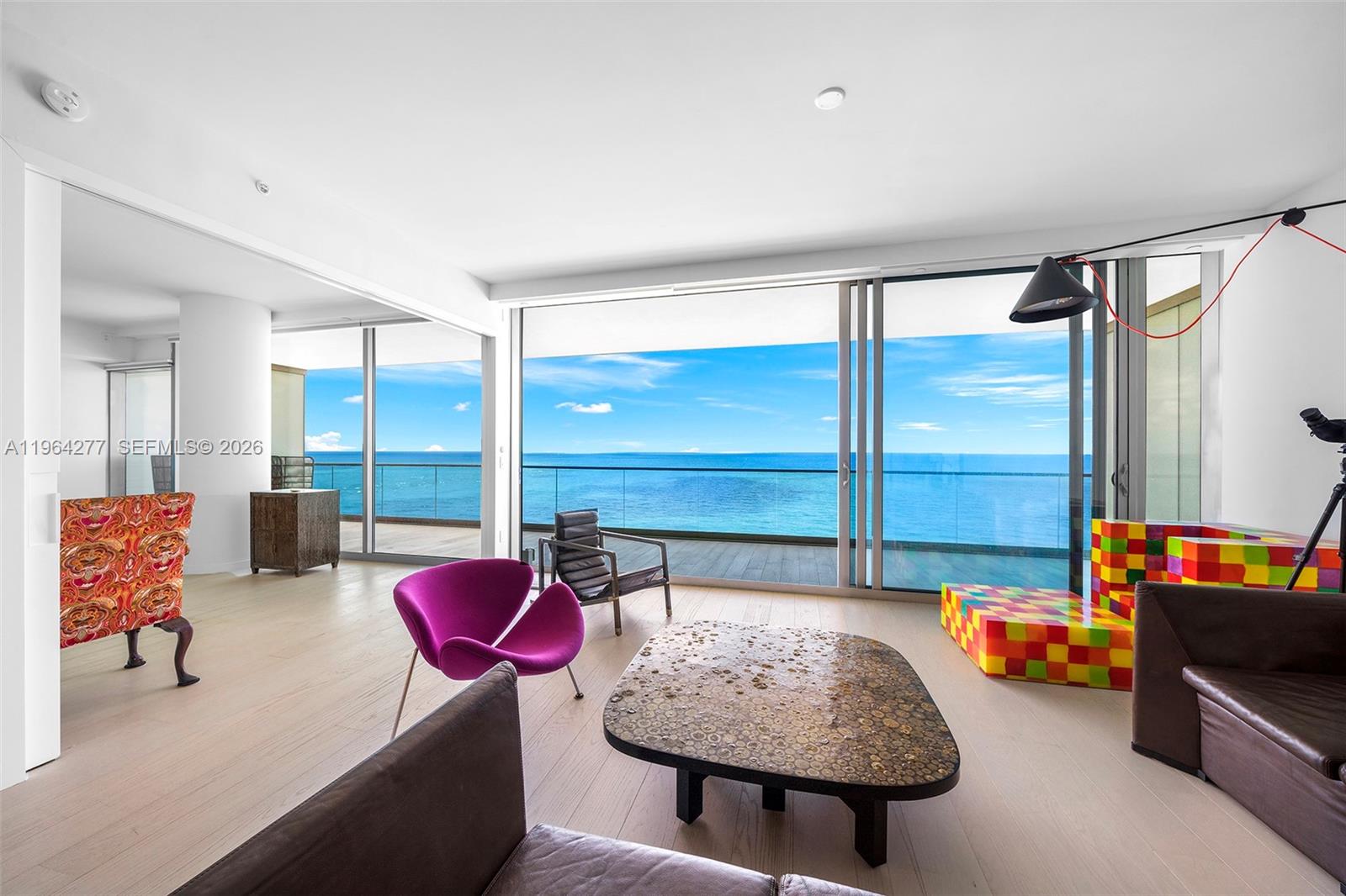 A modern living room features floor-to-ceiling windows with an expansive ocean view and balcony — 10203 Collins Ave # 1602, Bal Harbour FL 33154, BAL HARBOUR, FL