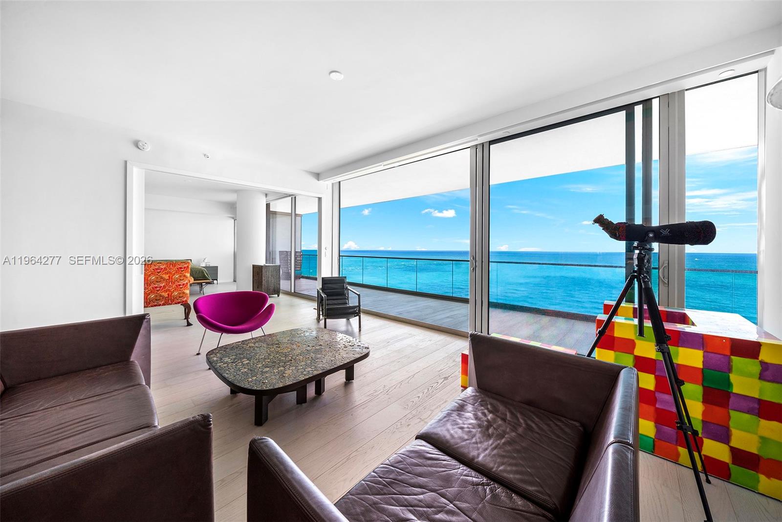 A living room features leather sofas, a coffee table, and floor-to-ceiling windows overlooking the ocean — 10203 Collins Ave # 1602, Bal Harbour FL 33154, BAL HARBOUR, FL