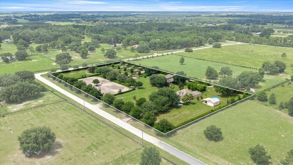 An aerial view shows a rural property with a house, outbuildings, and fenced horse paddocks — 6290 SE 178TH COURT, MORRISTON, FL