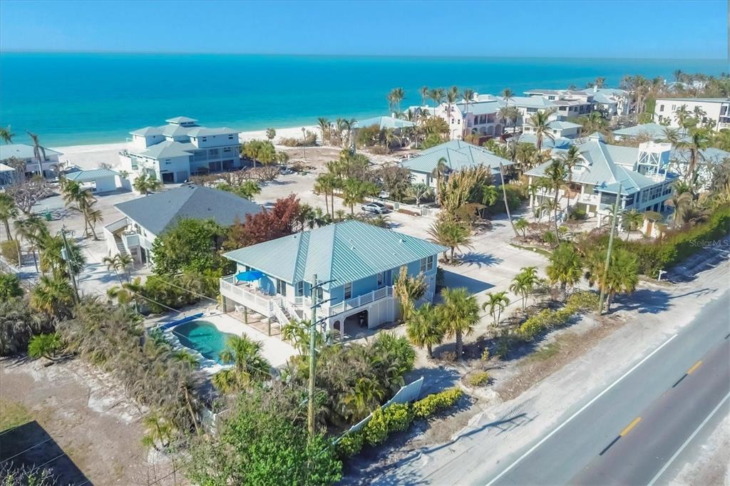 An aerial view shows a blue beach house with a pool near the ocean — 2420 24TH STREET W, BOCA GRANDE, FL
