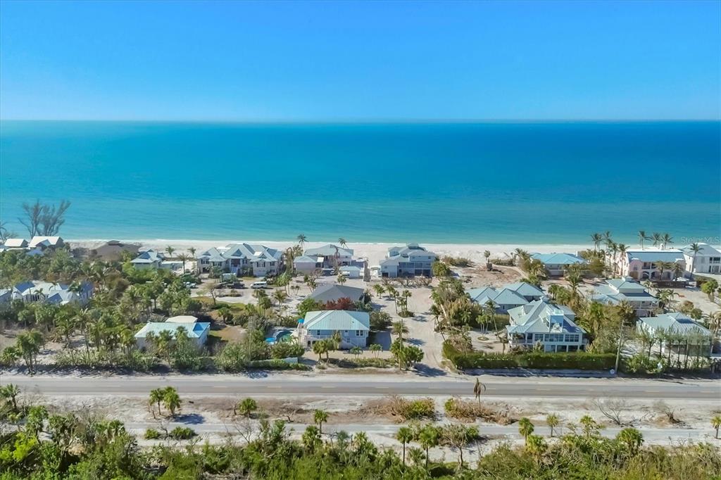 An aerial view of beachfront houses along a coastal road with palm trees and ocean — 2420 24TH STREET W, BOCA GRANDE, FL