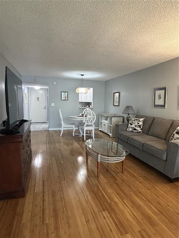 A living room and dining area with light wood floors, gray walls, and a sofa — 11485 OAKHURST ROAD UNIT 200-307, LARGO, FL