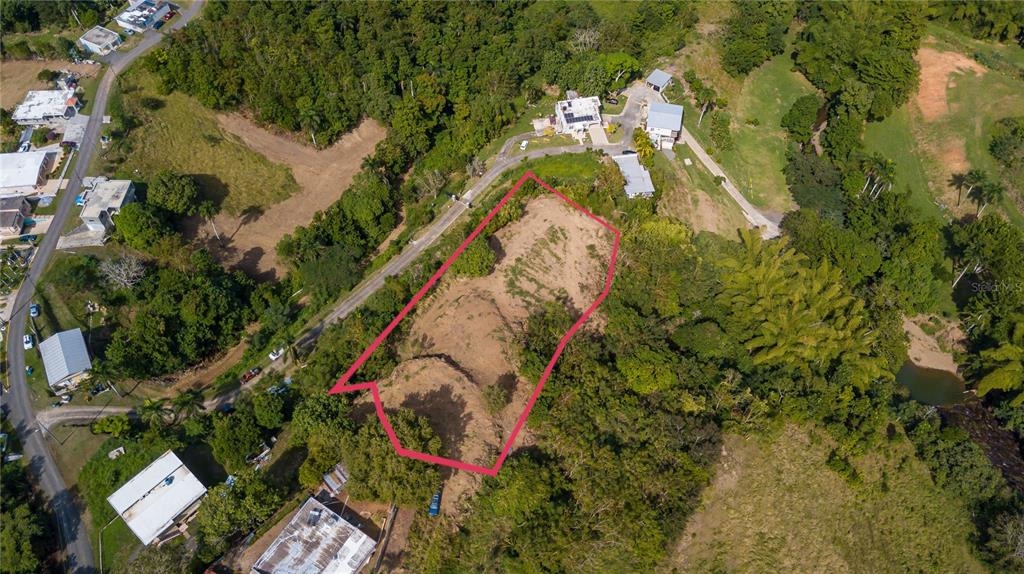 An aerial view shows a vacant, irregularly shaped plot of land outlined in pink — Solar B BARRIO JAGÜEY, AGUADA, PR