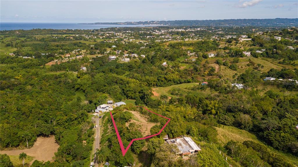 An aerial view shows a plot of land outlined in pink amidst lush green vegetation — Solar B BARRIO JAGÜEY, AGUADA, PR