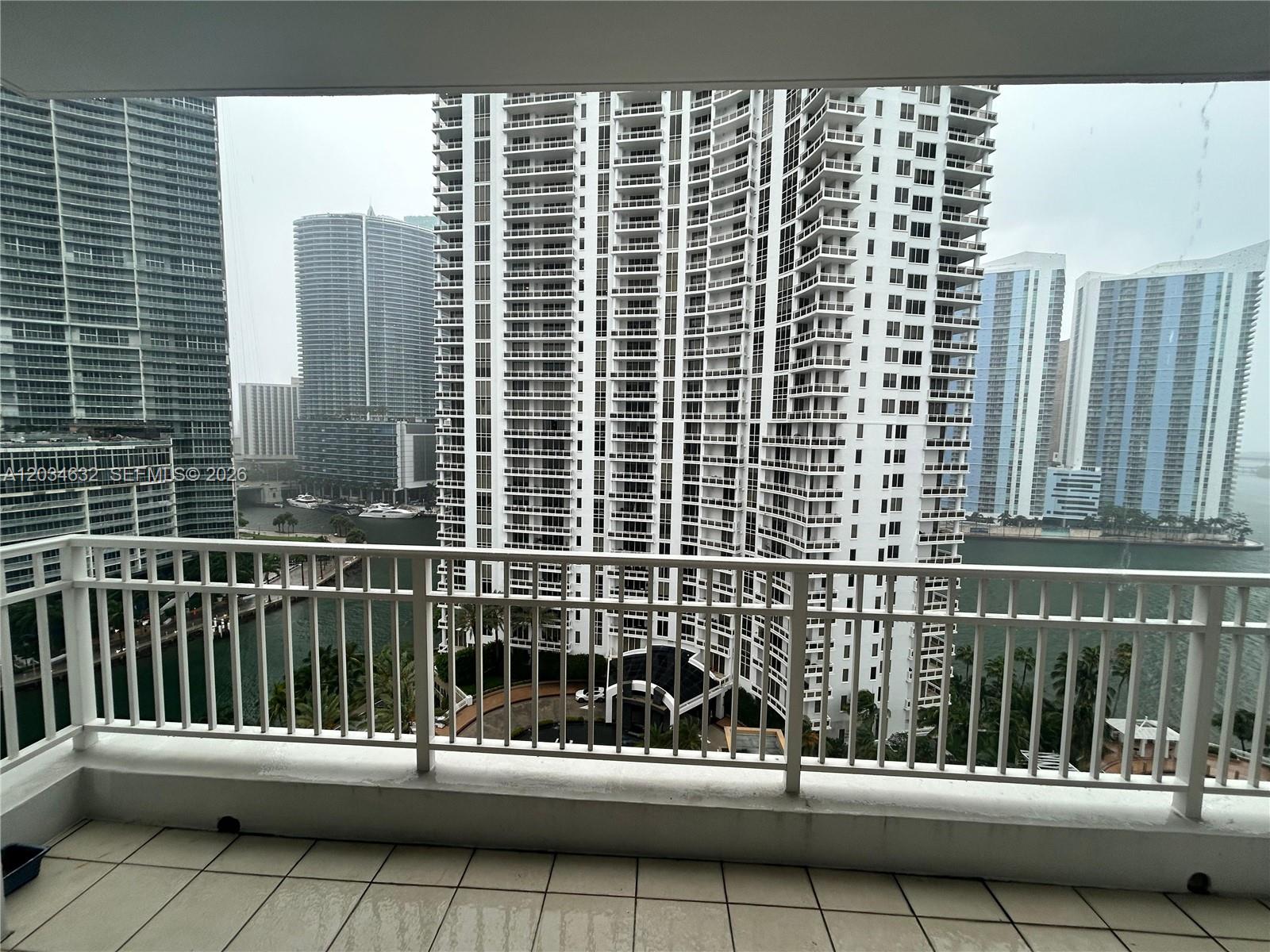 A balcony with a white railing overlooks a view of high-rise buildings and water — 801 Brickell Key Blvd # 1710, Miami FL 33131, MIAMI, FL