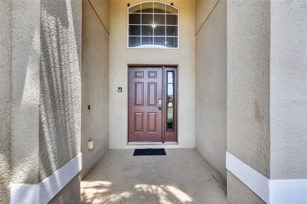 A brown front door with a side window is set within a recessed entryway — 130 SARAGOSSA AVENUE, DAVENPORT, FL