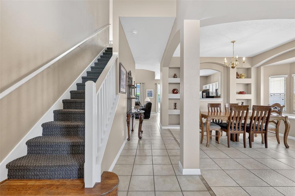 A tiled entryway features a carpeted staircase, a dining area, and built-in wall niches — 130 SARAGOSSA AVENUE, DAVENPORT, FL
