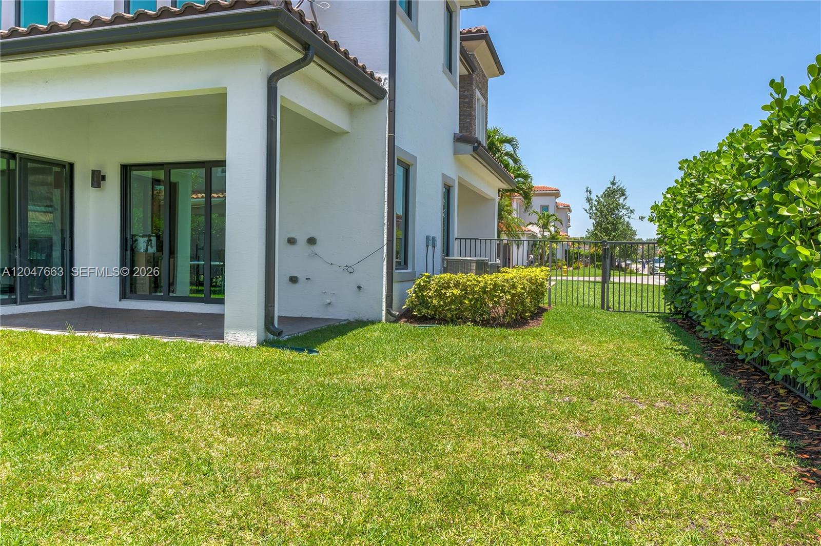 A backyard view shows a white house with a covered patio and a metal fence — 3412 Emerson Ln, Hollywood FL 33312, HOLLYWOOD, FL
