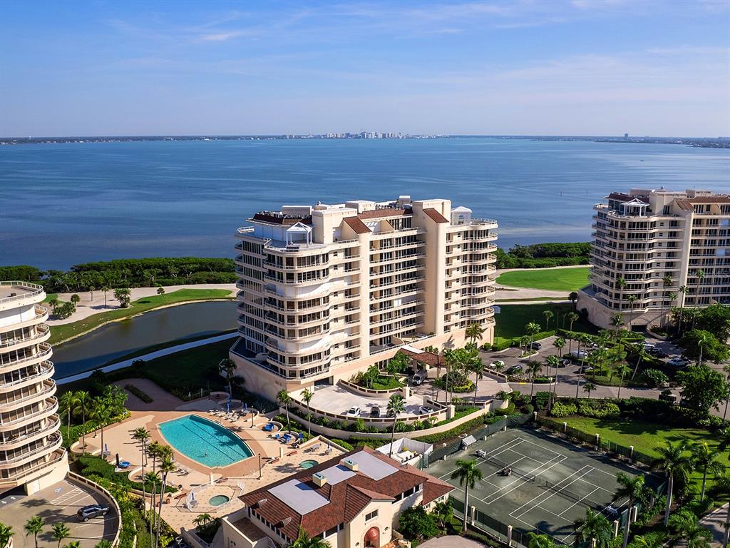 An aerial view of a multi-story residential building with a pool and golf course nearby — 3040 GRAND BAY BOULEVARD UNIT 213, LONGBOAT KEY, FL
