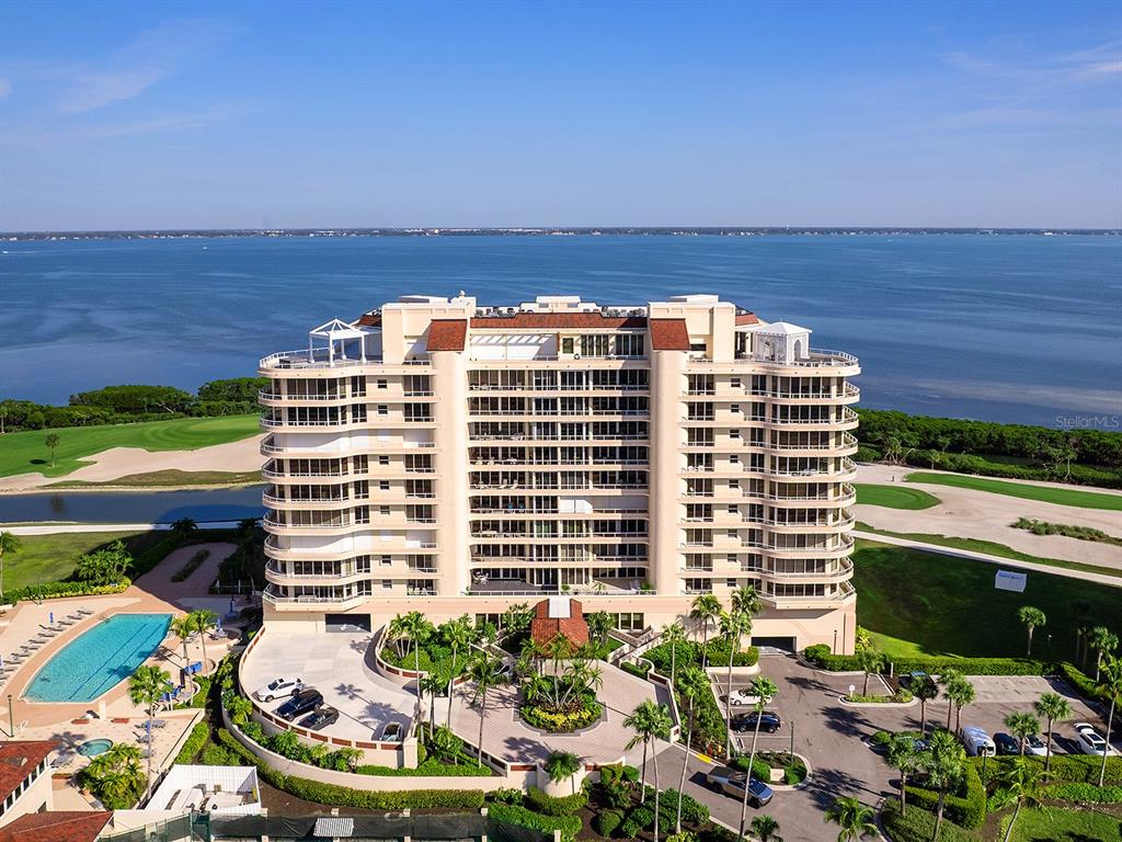A covered balcony features wicker furniture, tile flooring, and a view of a golf course — 3040 GRAND BAY BOULEVARD UNIT 213, LONGBOAT KEY, FL