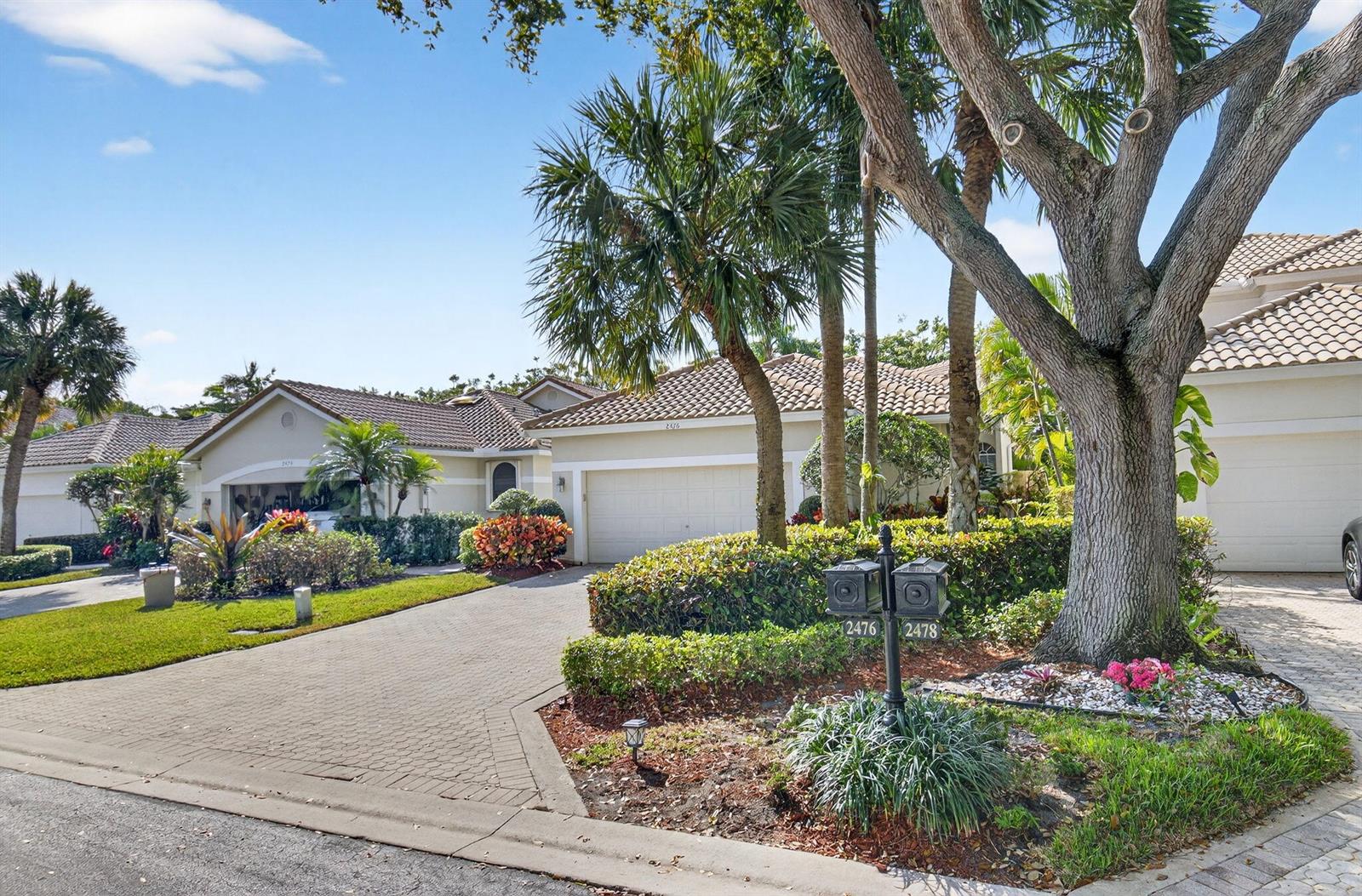 A paved driveway leads to two suburban homes with tiled roofs and lush landscaping — 2476 NW 66th Drive, Boca Raton FL 33496, BOCA RATON, FL