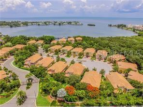 An aerial view shows a residential community with tan-roofed buildings near a large body of water — 184 BANYAN BAY DRIVE, ST PETERSBURG, FL