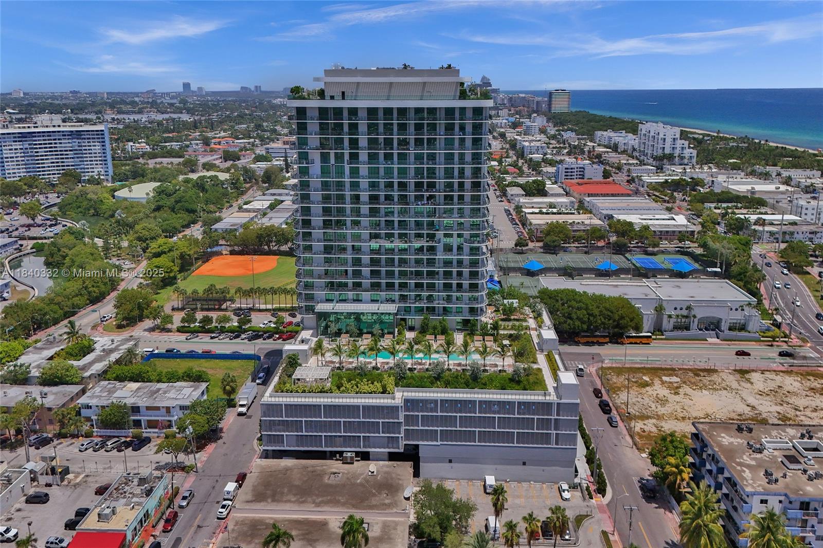An aerial view shows a modern high-rise residential building with a landscaped pool deck — 580 72nd St # 1208, Miami Beach FL 33141, MIAMI BEACH, FL