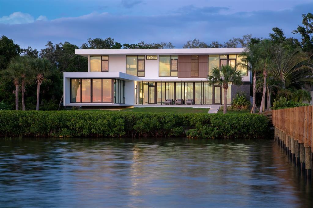 A modern two-story waterfront home with large glass windows and a wooden dock — 1500 BAYVIEW DRIVE, SARASOTA, FL