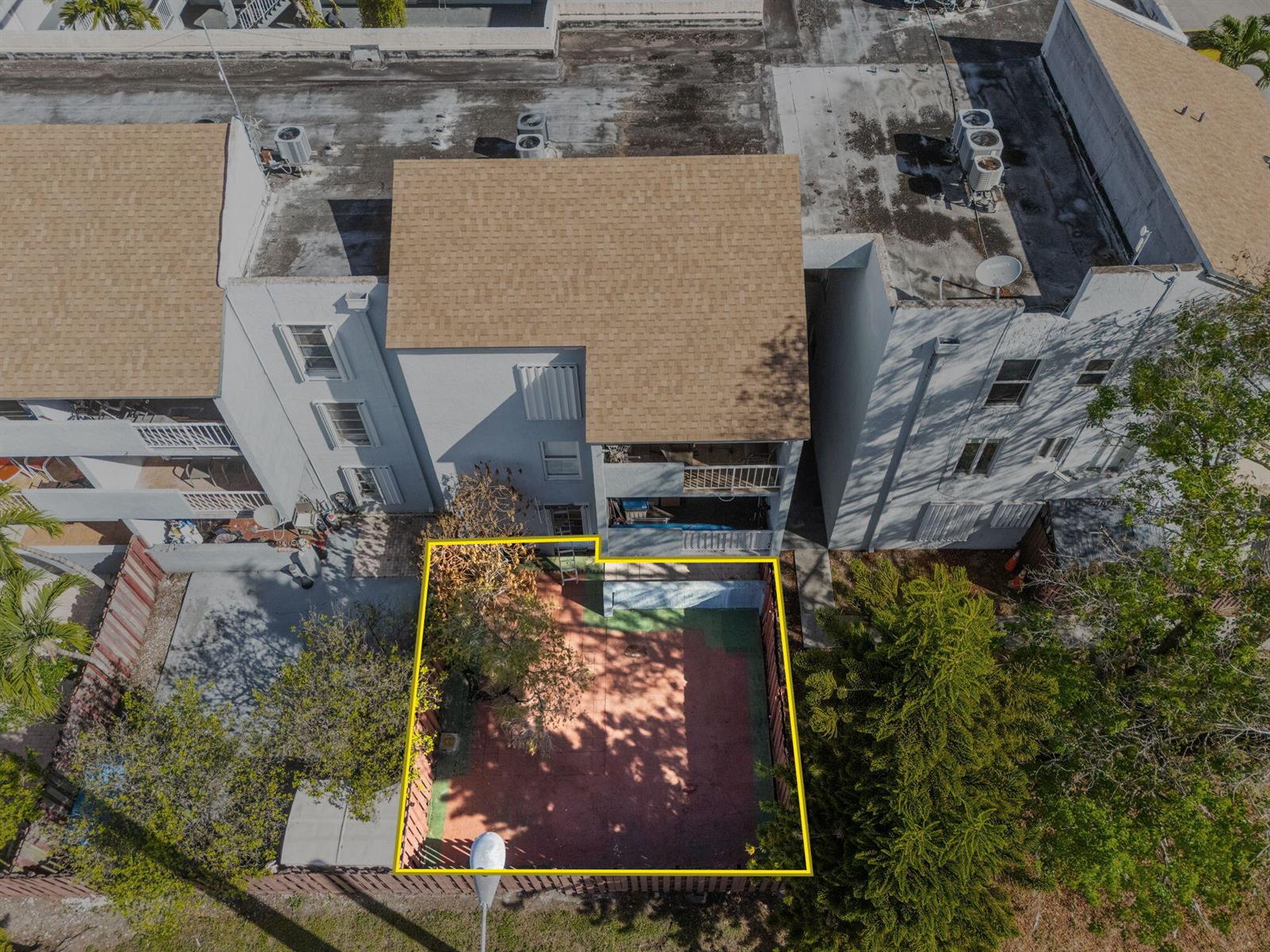 An aerial view shows a fenced-in backyard patio area behind a multi-story residential building — 1725 W 60th Street # F126, Hialeah FL 33012, HIALEAH, FL