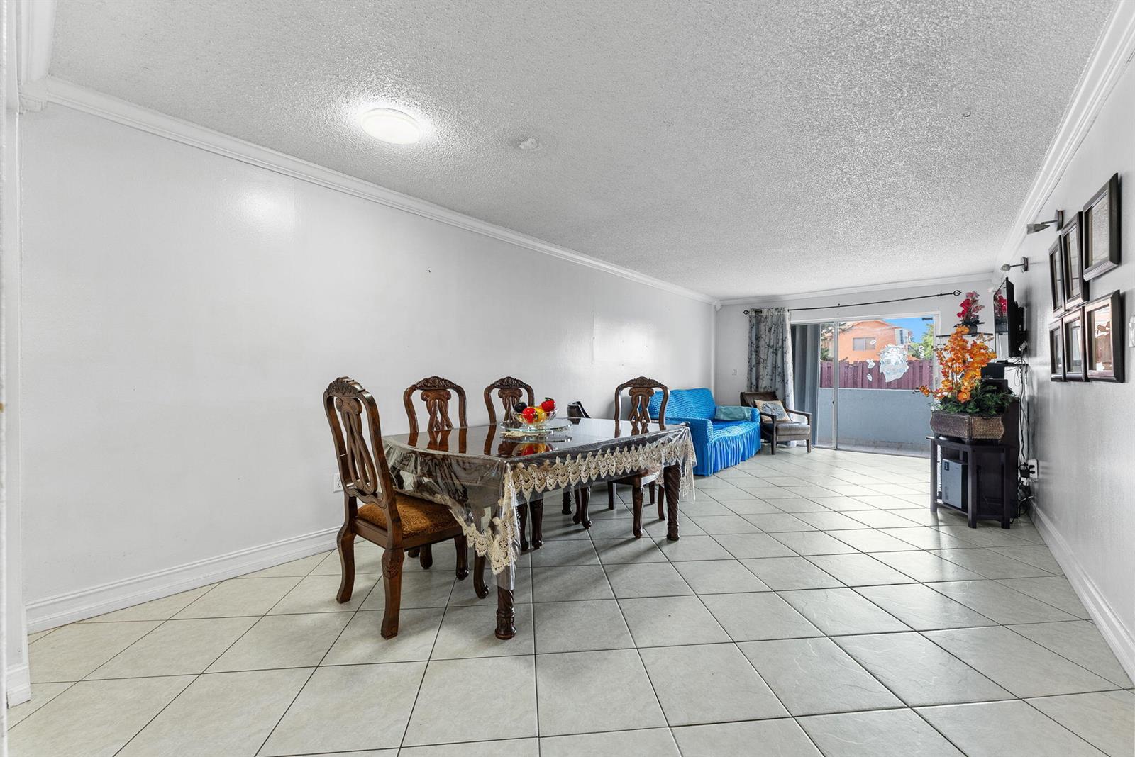 A dining area with a wooden table and chairs sits on tiled floors near a living room — 1725 W 60th Street # F126, Hialeah FL 33012, HIALEAH, FL
