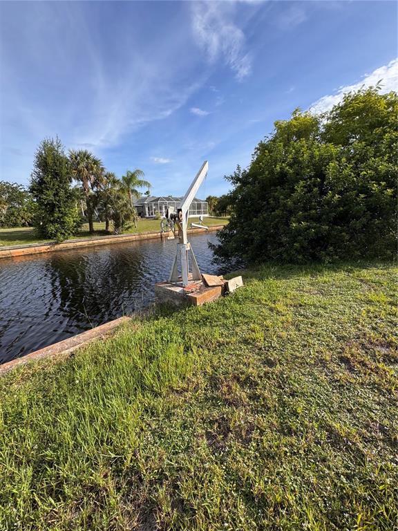A vacant, grassy residential lot sits under a blue sky with scattered clouds — 3016 SHANNON DRIVE, PUNTA GORDA, FL