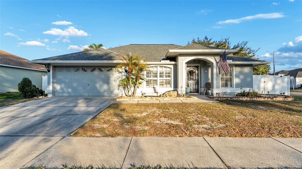 A single-story gray house with a two-car garage, arched entryway, and an American flag — 5410 LINDBURG STREET, RIVERVIEW, FL