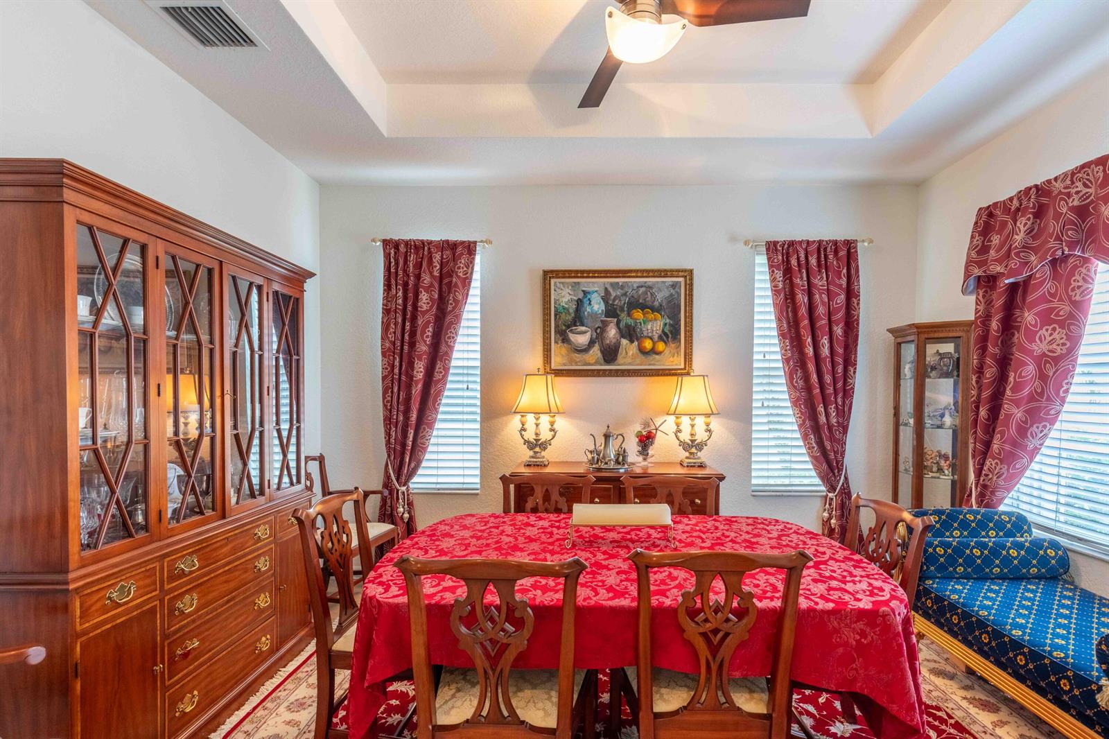 A formal dining room features a wooden hutch, a table with a red tablecloth, and curtains — 4376 NW Oakbrook Circle, Jensen Beach FL 34957, JENSEN BEACH, FL