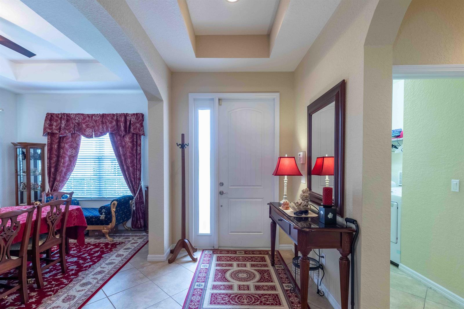 An entryway features a white front door, a console table with a mirror, and tile flooring — 4376 NW Oakbrook Circle, Jensen Beach FL 34957, JENSEN BEACH, FL
