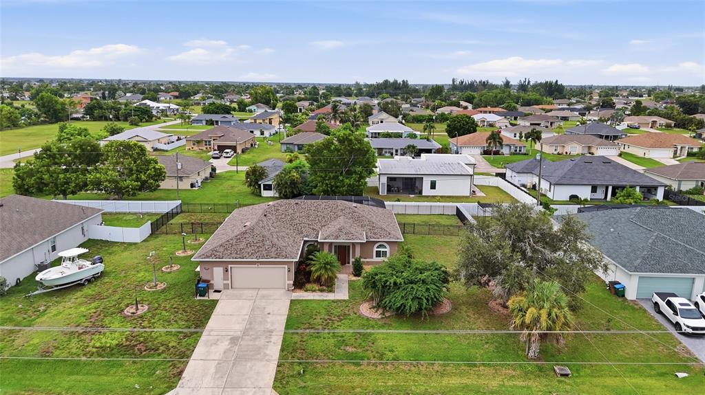 An aerial view shows a suburban single-family home with a driveway, lawn, and surrounding neighborhood — 219 NW 12TH LANE, CAPE CORAL, FL