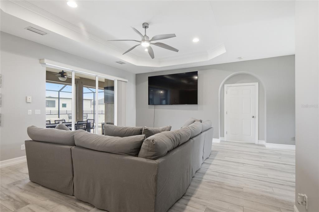 A living room features a large gray sectional sofa, a wall-mounted television, and tile flooring — 219 NW 12TH LANE, CAPE CORAL, FL