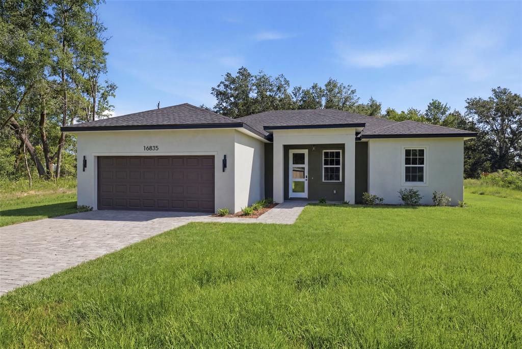 A single-story house with a paved driveway, a two-car garage, and a white stucco exterior — 16835 SW 17TH TERRACE, OCALA, FL