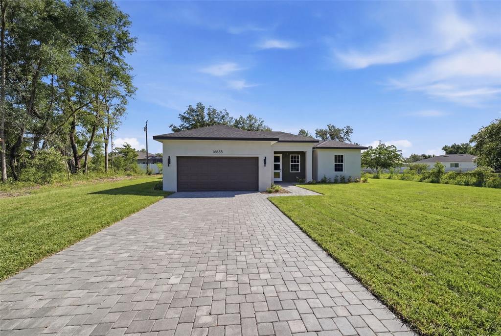 A single-story house with a paved driveway, a two-car garage, and a light-colored exterior — 16835 SW 17TH TERRACE, OCALA, FL