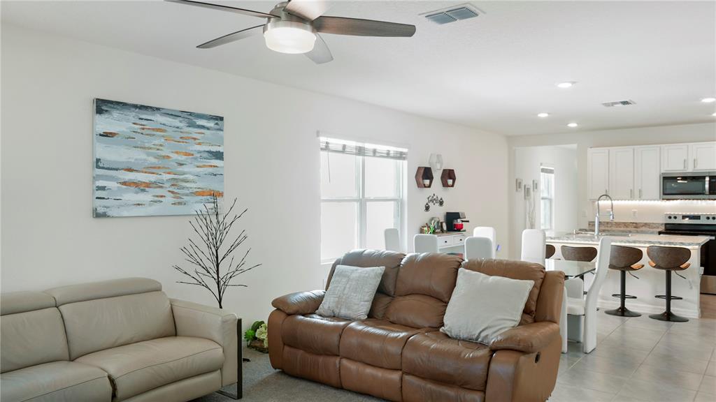 A living room with a brown leather sofa and a beige sofa faces an open kitchen — 1302 HOLODAK DRIVE, DAVENPORT, FL