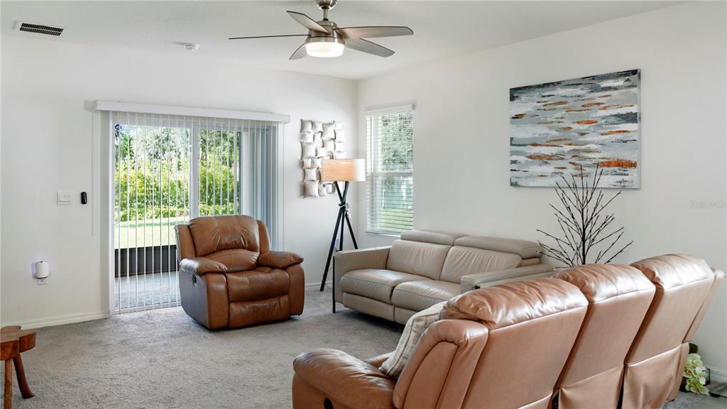 A living room features a leather recliner, a light-colored sofa, and a sliding glass door — 1302 HOLODAK DRIVE, DAVENPORT, FL