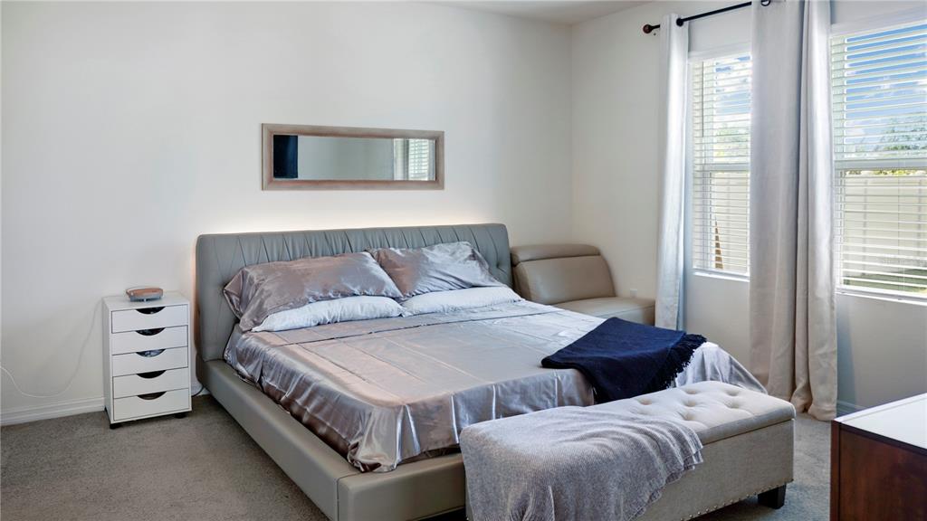 A bedroom features a gray upholstered bed, a white nightstand, and a tufted storage bench — 1302 HOLODAK DRIVE, DAVENPORT, FL